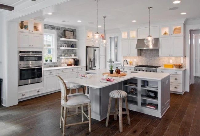 A bright kitchen with a white island featuring stools for seating across from one another.