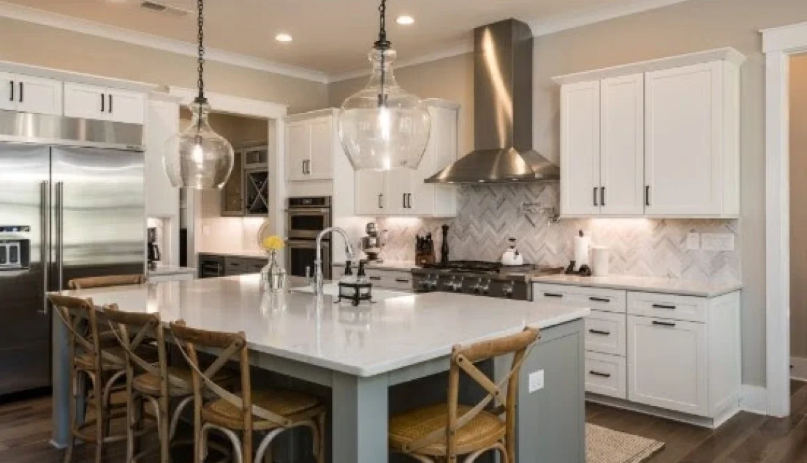 A white kitchen island with stools for family gatherings, surrounded by modern appliances and pendant lights in a cozy kitchen.