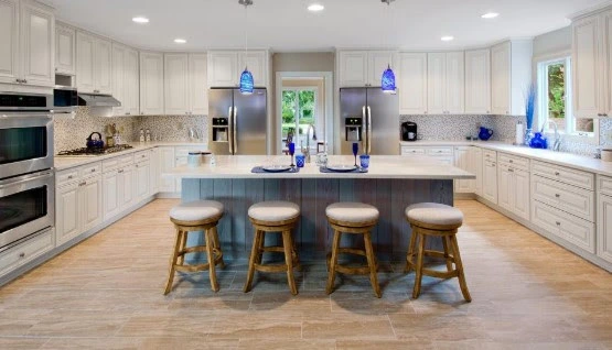 A spacious kitchen with a white island featuring corrugated metal siding along the face for a fun industrial vibe, paired with blue pendant lights.