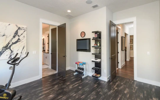Cozy fitness room with a stationary bike, weights, and a TV, ideal for retirees embracing new hobbies.