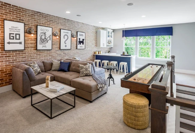 : Inviting game room with a shuffleboard table, sofa, and brick wall, ideal for retirees seeking personal space.